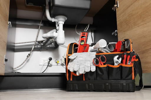 Plumber's tool bag on the floor under the kitchen sink.