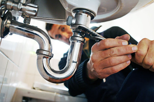 Image of an HVAC contractor looking at the pipes under a sink.
