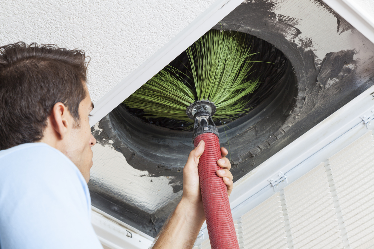 Technician performing air duct cleaning in Baltimore, using a specialized tool to clean and remove debris from an HVAC system duct.