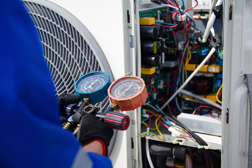 The air conditioner technician is using a gauge to measure the refrigerant pressure air compressor.