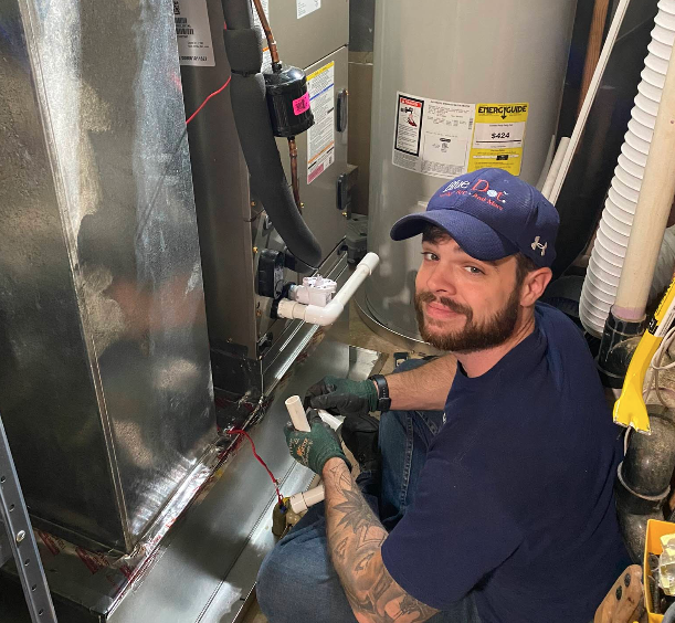 Blue Dot HVAC technician performing repairs on an HVAC system, smiling while working with tools and equipment.