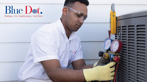 Blue Dot HVAC technician checking refrigerant levels on an outdoor AC unit using manifold gauges.